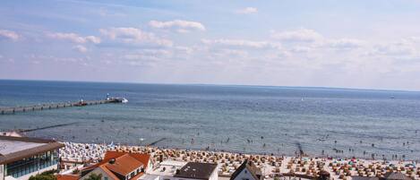 Eine Küstenstadt mit Strand, Steg und Wohnhäusern.