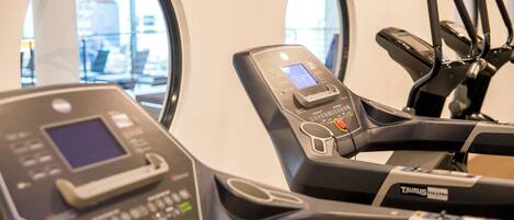 A gym with exercise equipment, including a treadmill and a stationary bike, with a digital display and control panel.