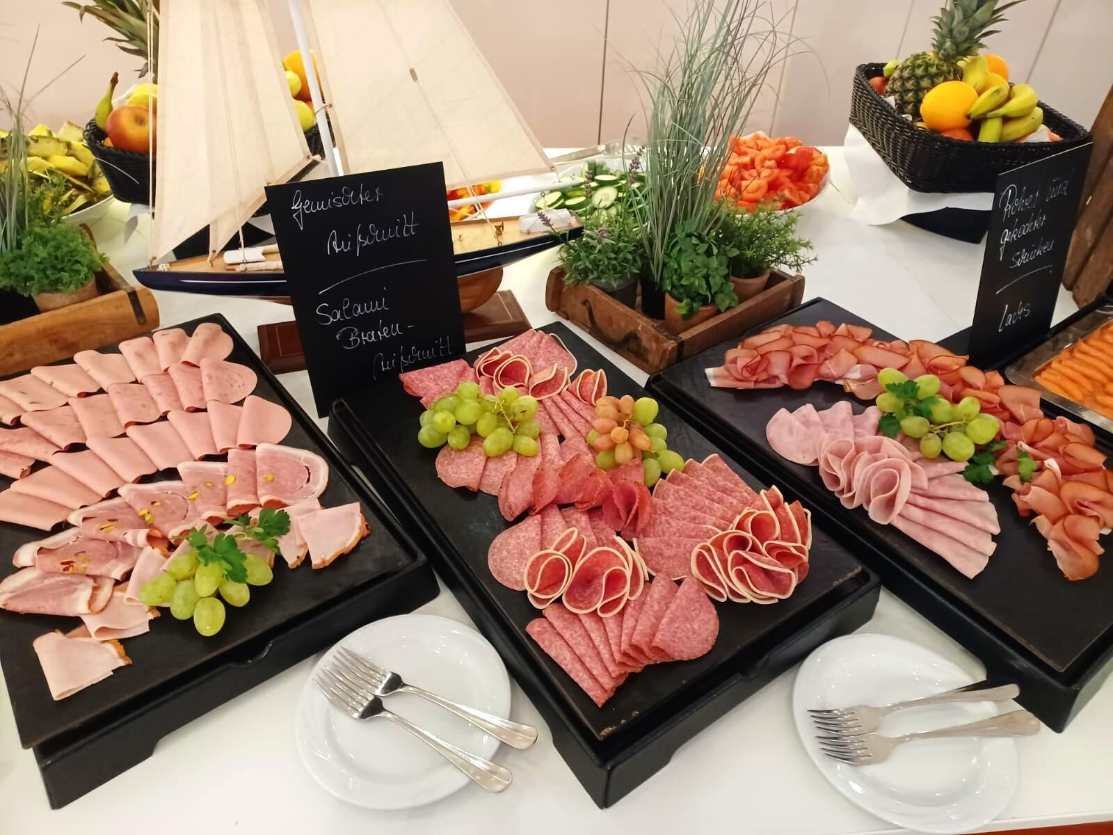 Un bufé con carnes y frutas variadas.