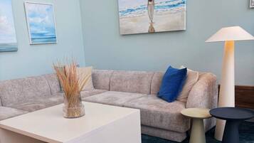 A modern living room with a beige sofa, a white coffee table, and a lamp.