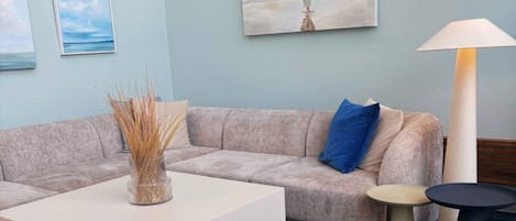 A modern living room with a beige sofa, a white coffee table, and a lamp.