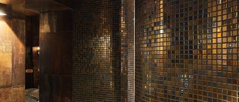 A corridor with dark tiled walls and a polished floor, leading to a room with a large window.