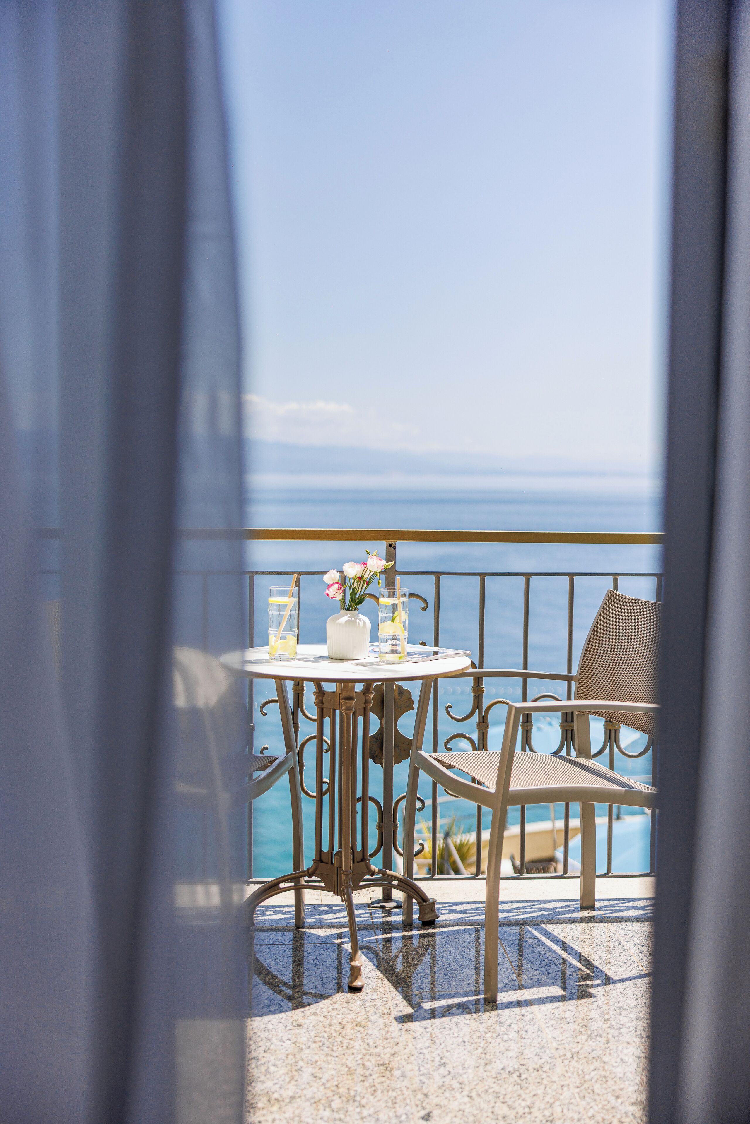 Un balcon avec une table et des chaises, donnant sur une étendue d’eau.