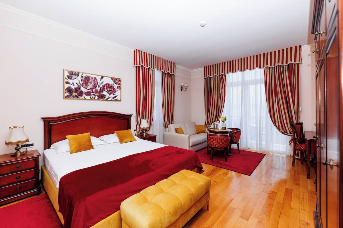 A hotel room with a large bed, a bench, a desk, and a chair.