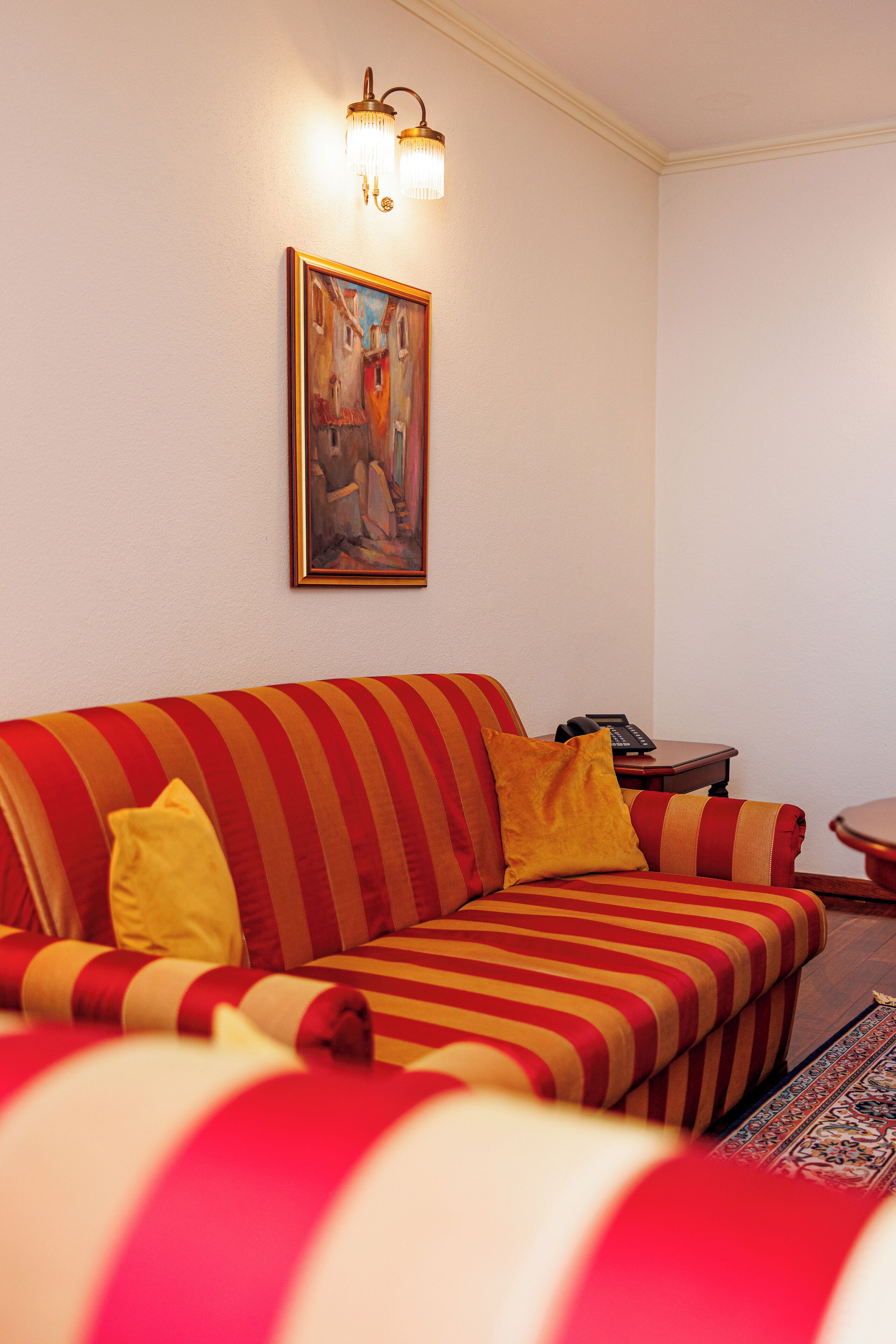 A striped sofa with a telephone and a small table beside it.