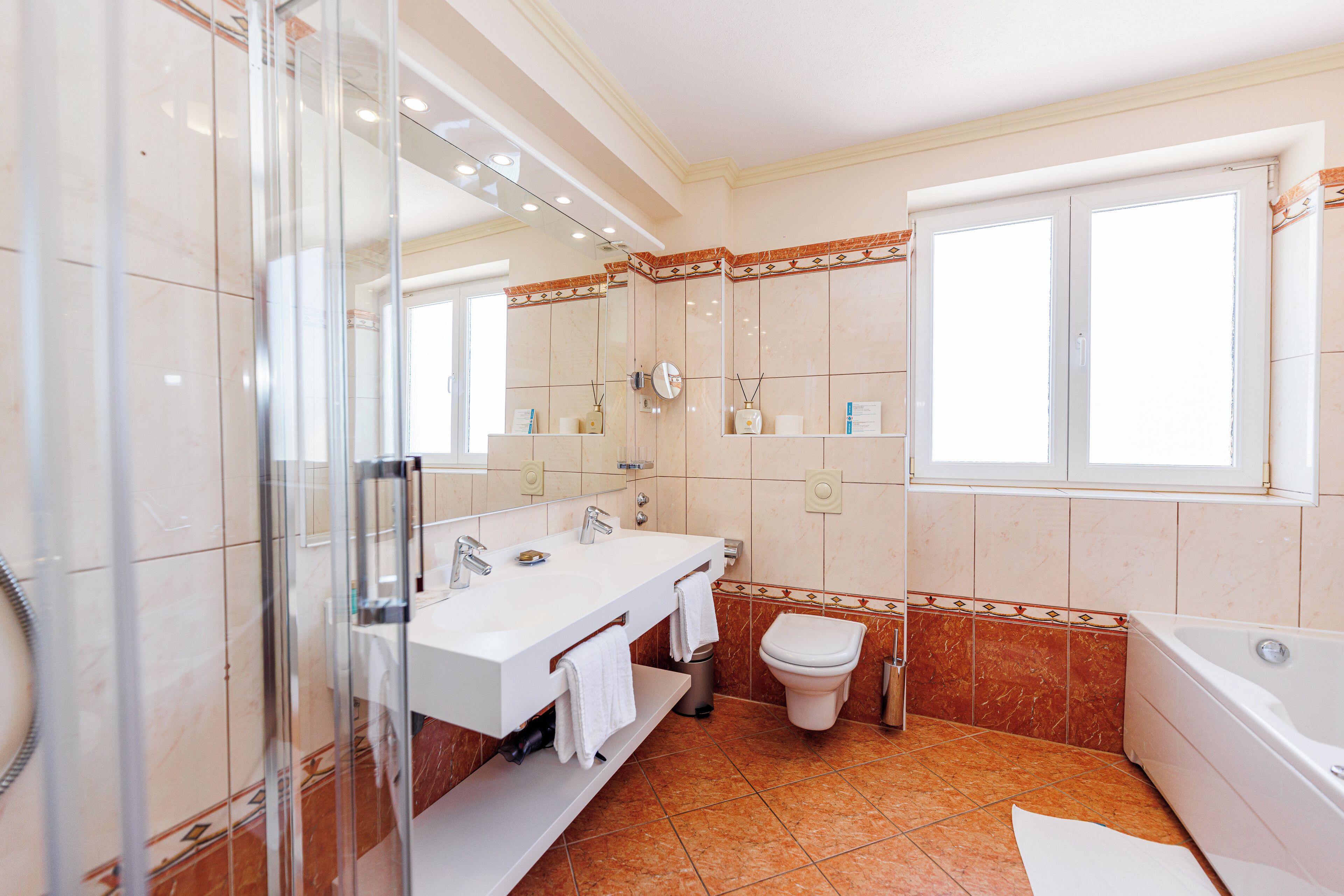 Un baño moderno con ducha de vidrio, tocador doble, inodoro y bañera.