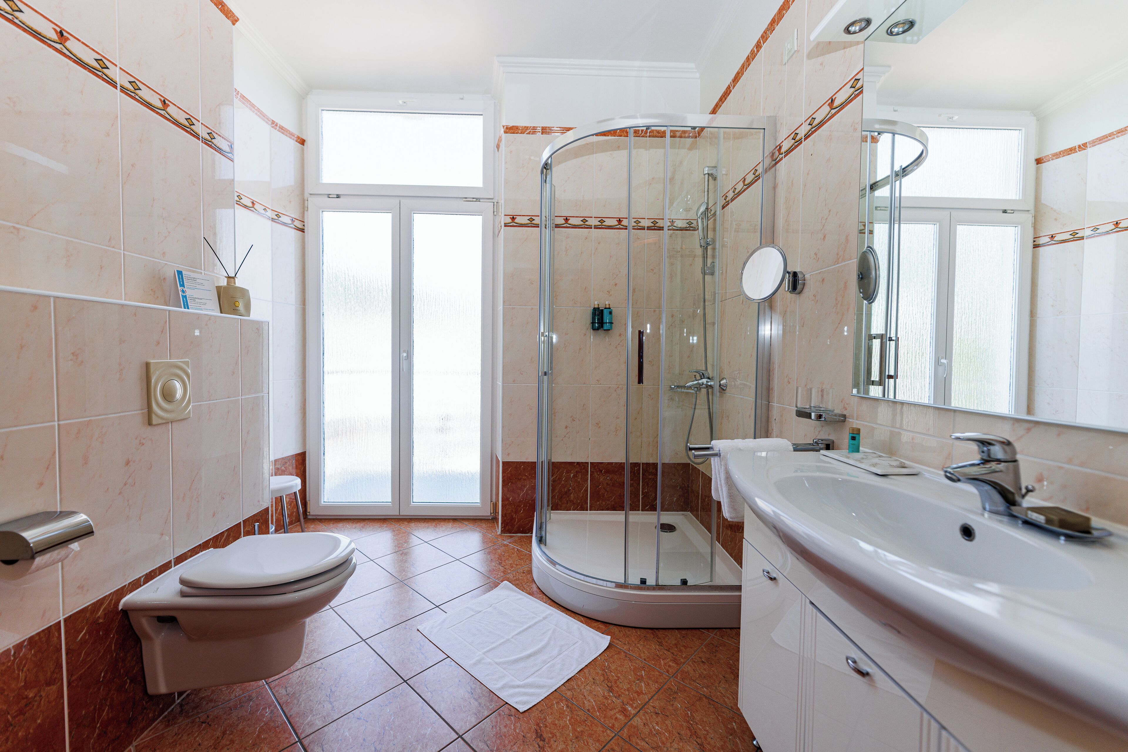 Een badkamer met een douchecabine, toilet, wastafel en spiegel.