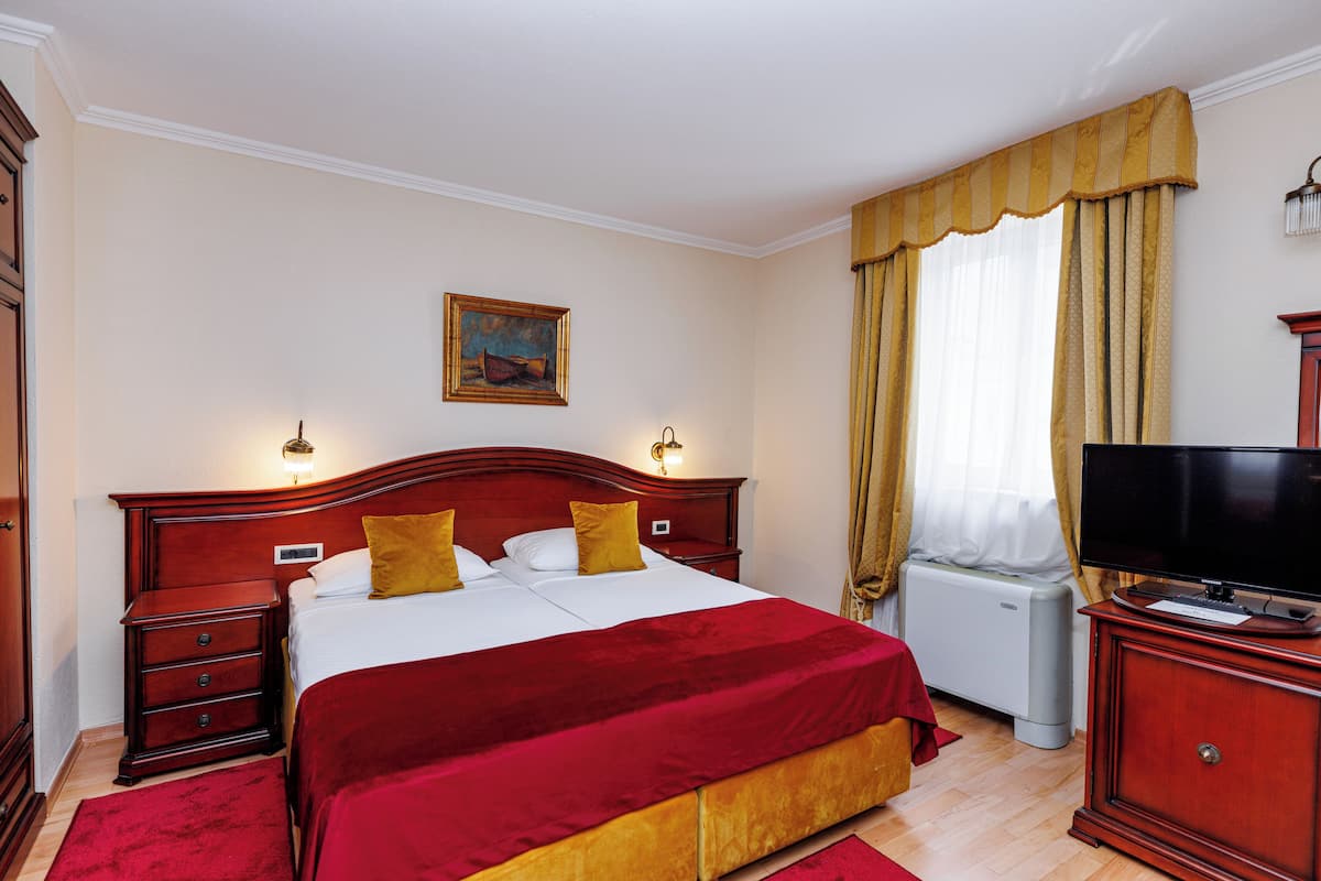 A hotel room with a large bed, a television, a nightstand, and a dresser.