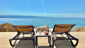 Two lounge chairs facing a seaside view with a table between them, a glass of drink, and a cup on the table. - Hotel Savoy (Opatija)