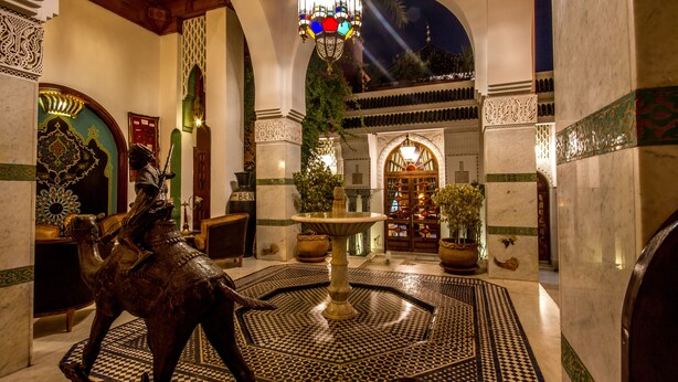 Un hall d’entrée agrémenté d’une fontaine, d’une statue de chameau et de motifs complexes en mosaïque.