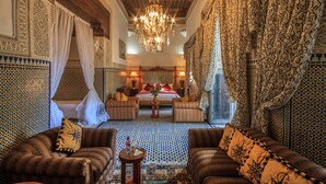 Une pièce traditionnelle marocaine avec un sol à motifs, un lustre et un lit à baldaquin.