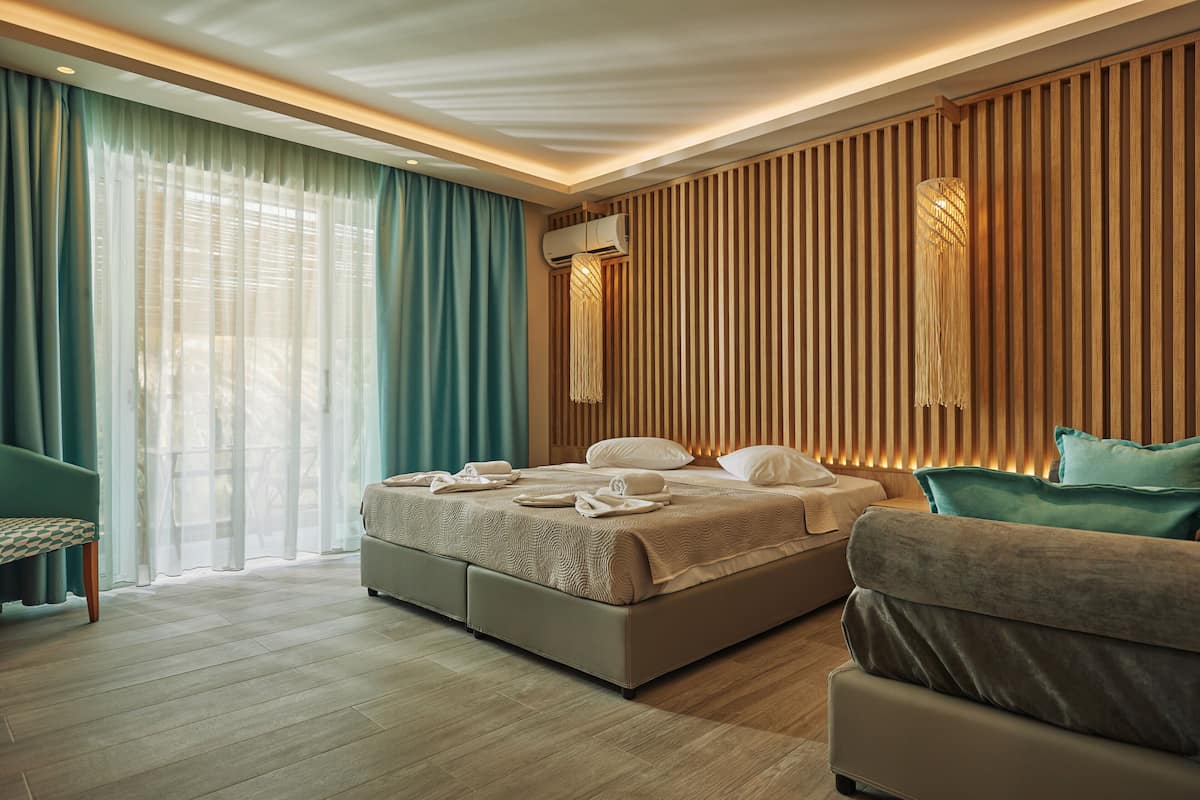 A modern hotel room with a large bed, a sofa, and a bench.