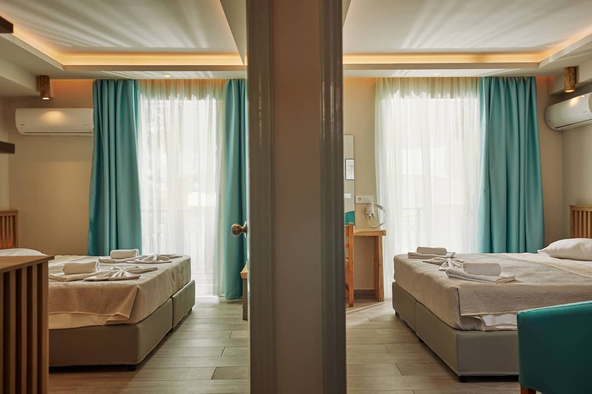 A hotel room with two beds, a desk, and a chair.
