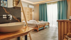 A hotel room with a large oval sink, wooden furniture, a bed with towels, and a view of the outdoors through curtains.