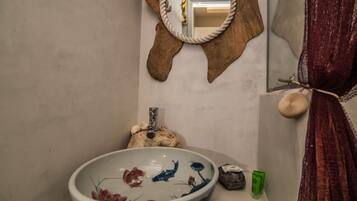 Un bagno con un lavandino decorativo di grandi dimensioni, uno specchio con cornice in corda e un porta asciugamani con un asciugamano.