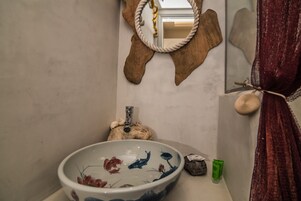 Un bagno con un lavandino decorativo di grandi dimensioni, uno specchio con cornice in corda e un porta asciugamani con un asciugamano.