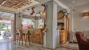 A spacious interior with a bar area, wooden stools, and a leather armchair.