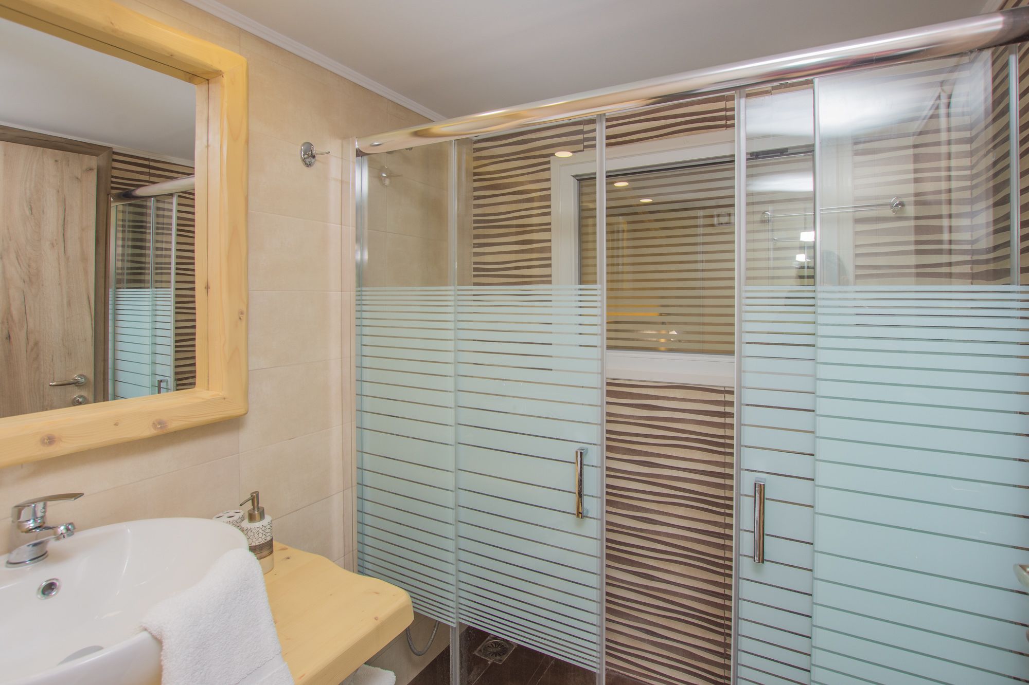 A bathroom with a sink, mirror, and glass shower enclosure.