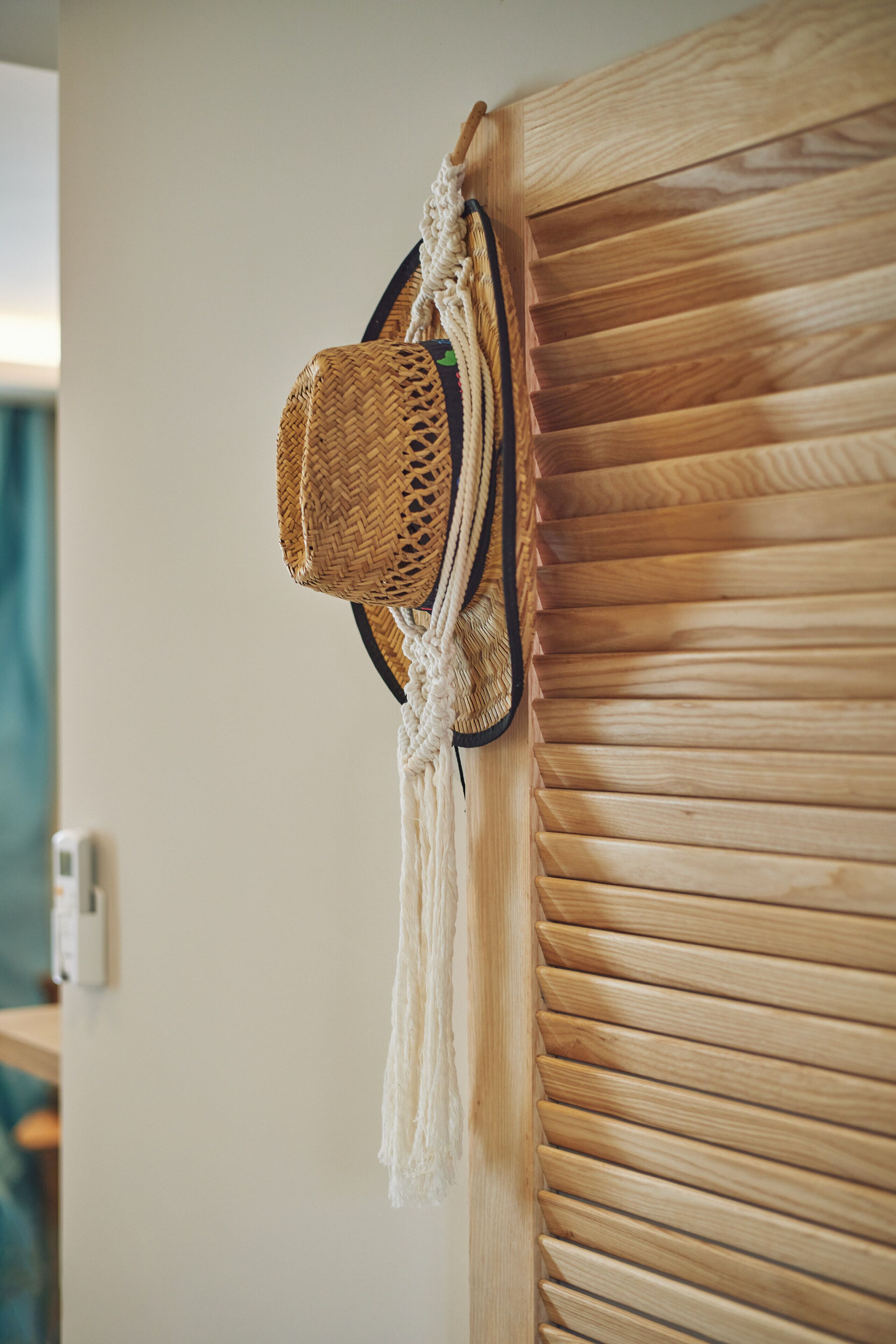 Une porte en bois ornée d’un panier tressé et d’une décoration en macramé.