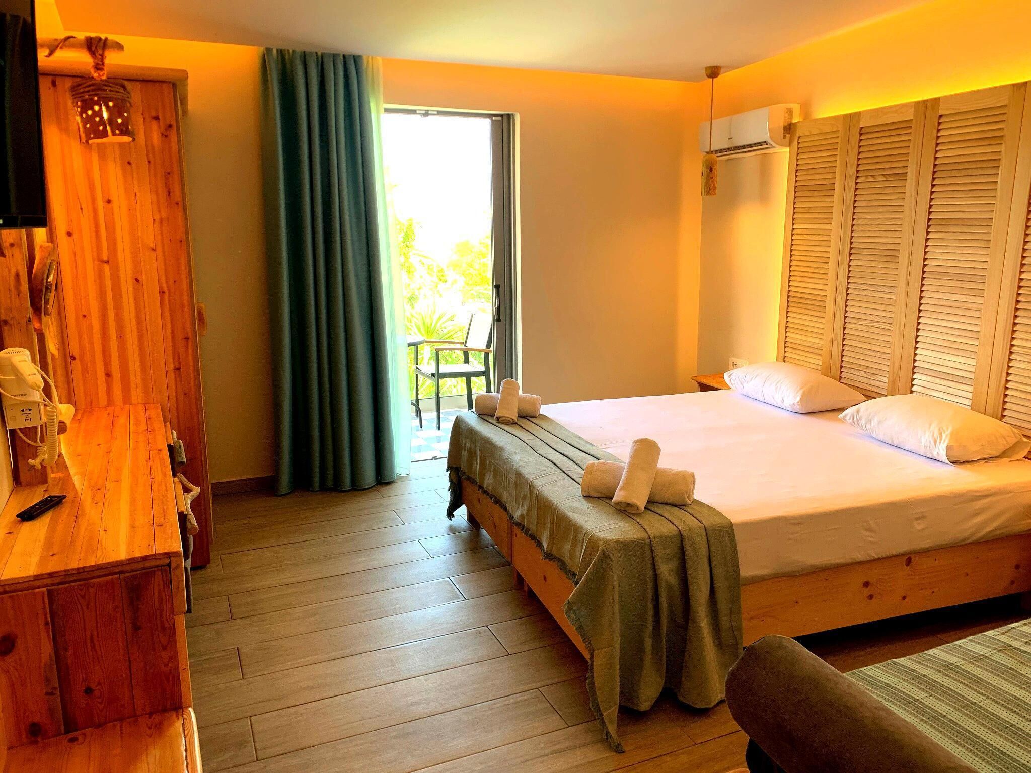 A room with a bed, a wooden desk, a chair, and a window with curtains.
