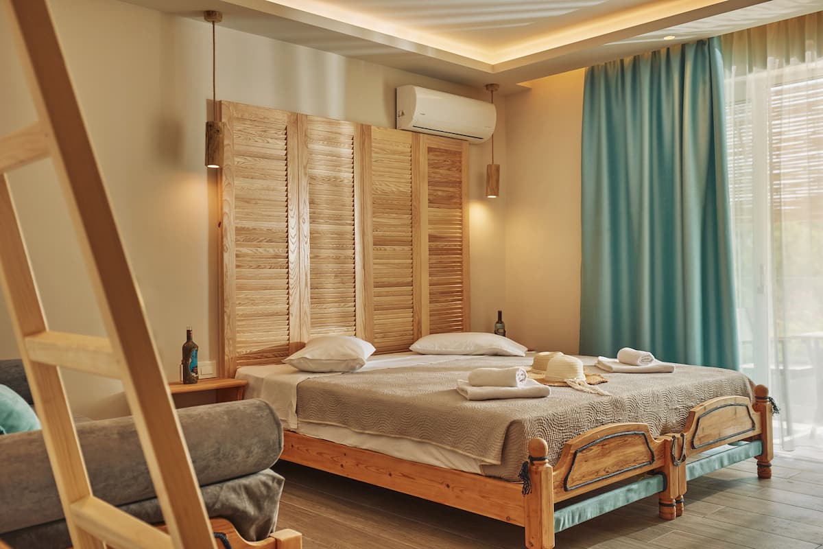 A wooden bed with a headboard, a bedside table with a bottle, and a window with curtains.