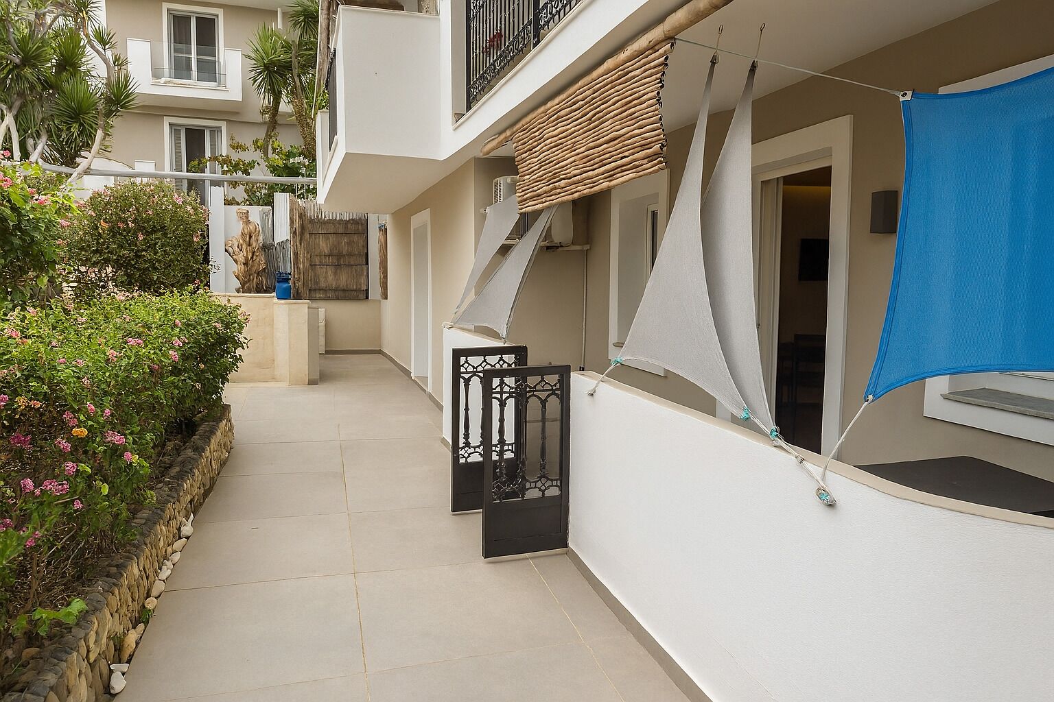 Un edificio residencial con un patio estrecho, un balcón con persiana de mimbre y un paño azul colgando a la derecha.