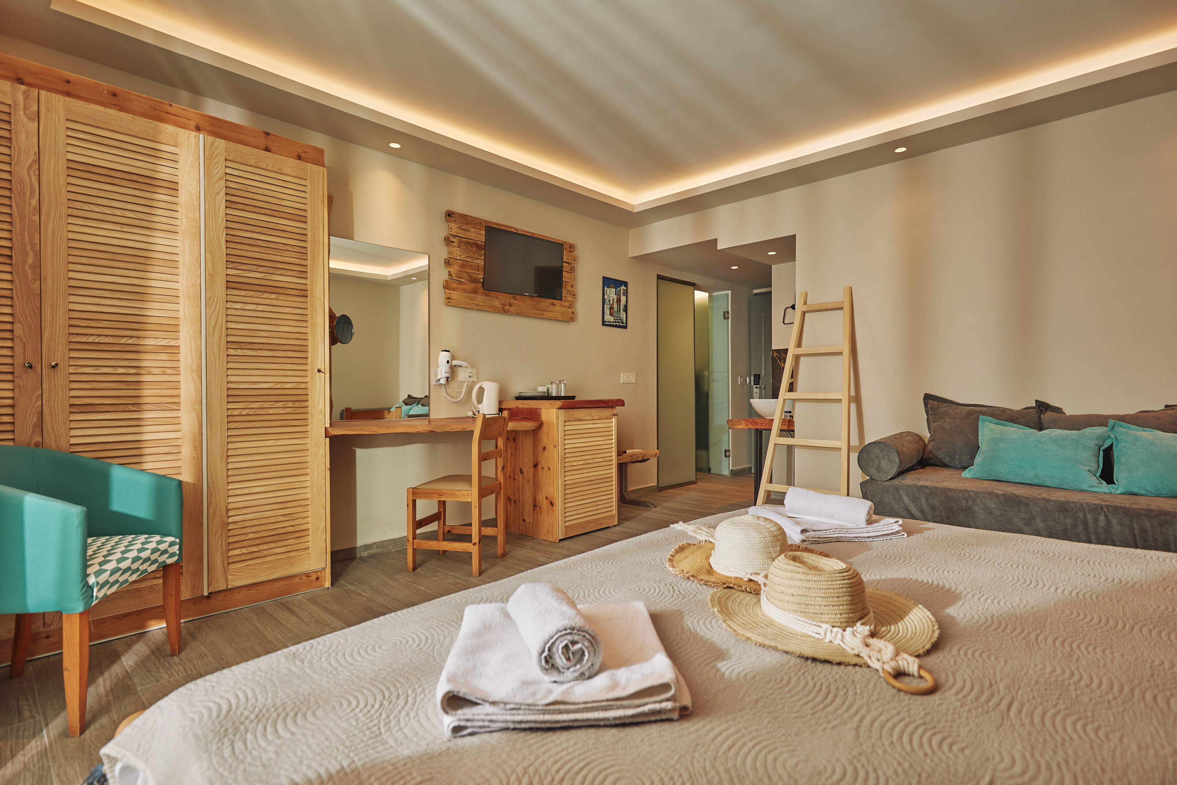 Een hotelkamer met een bed, een bureau, een stoel, een kledingkast en een badkamer, zichtbaar door een geopende deur.