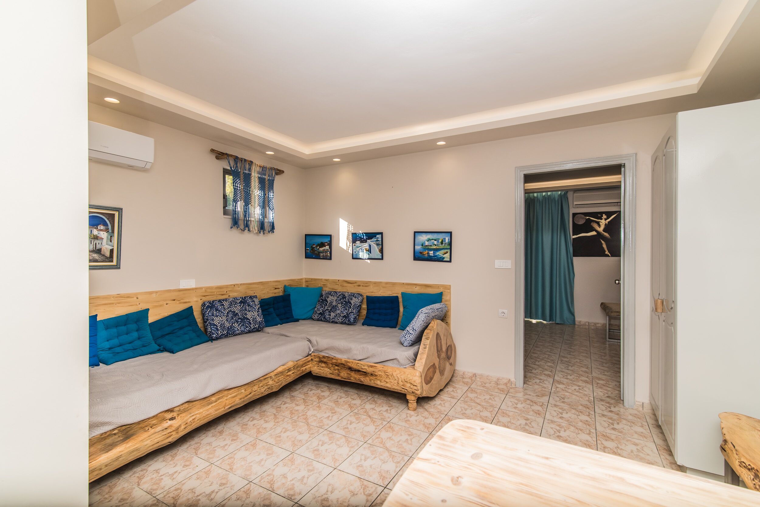 A modern room with a wooden sofa, a small table, and a door leading to a bathroom.