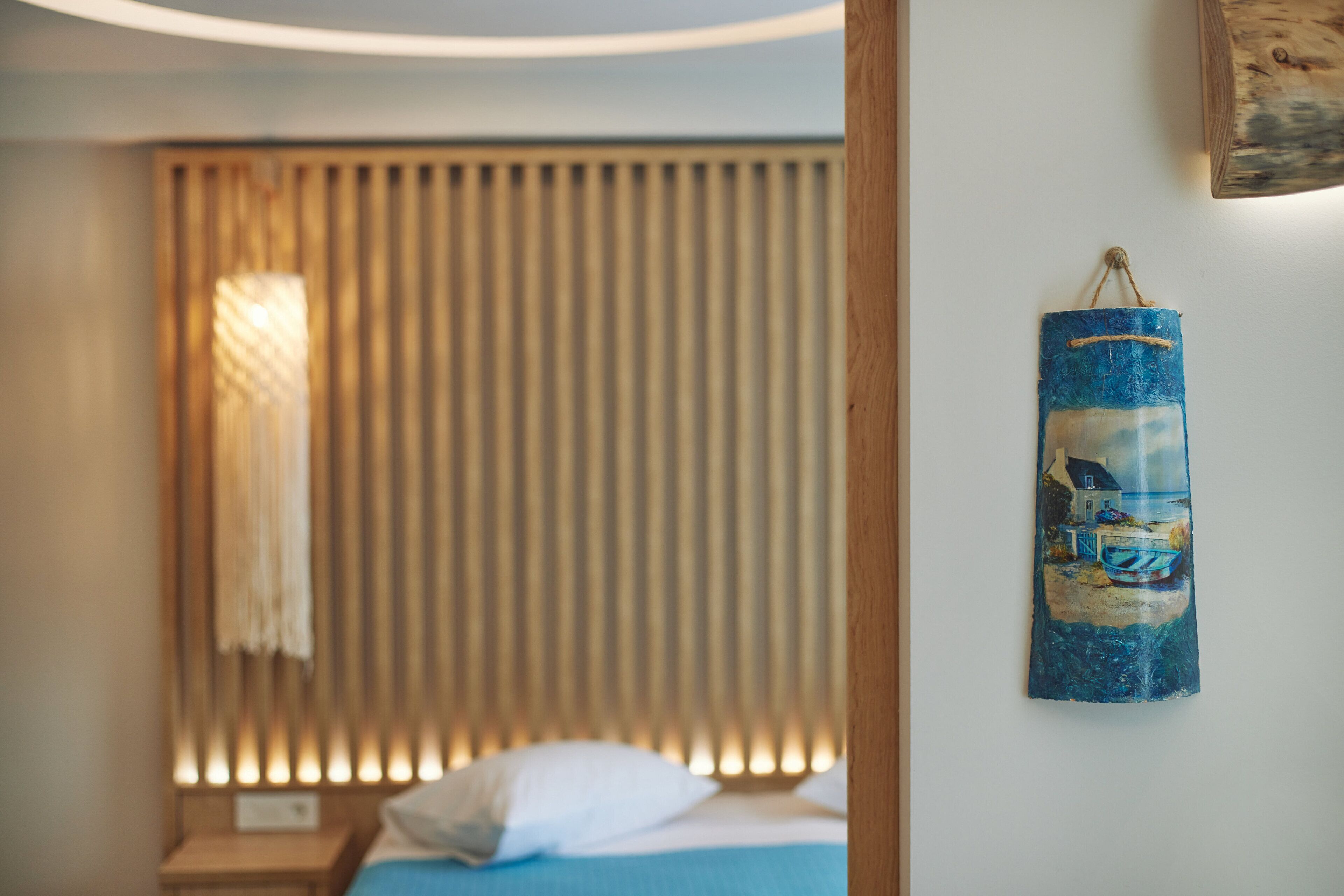 Une chambre à coucher avec un lit, une fenêtre avec des stores et une œuvre d’art accrochée au mur.