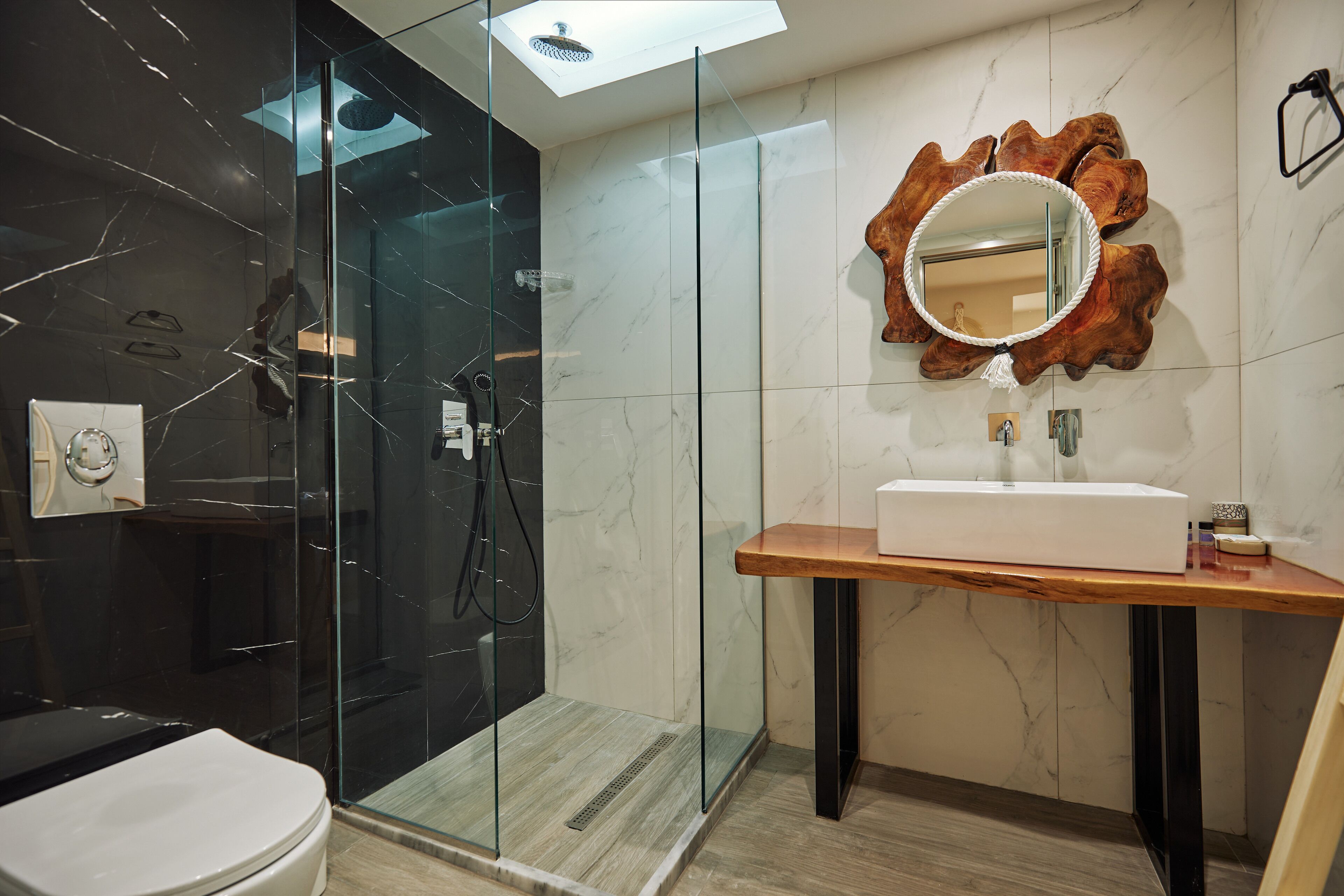 Un bagno moderno con doccia vetro, mobile lavabo in legno con lavandino bianco e uno specchio in legno originale.