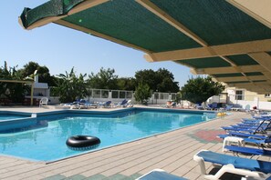 Una piscina al aire libre, sombrillas, tumbonas