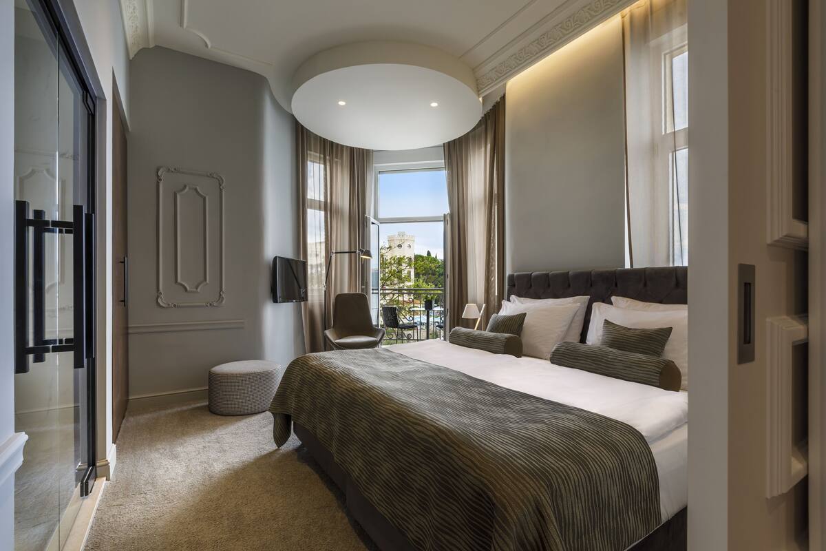 A spacious bedroom with a large bed, a chair, and a view of the outdoors.