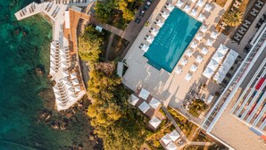 Vista aérea de un hotel con piscina, zonas de estar al aire libre y ubicación frente a la playa.