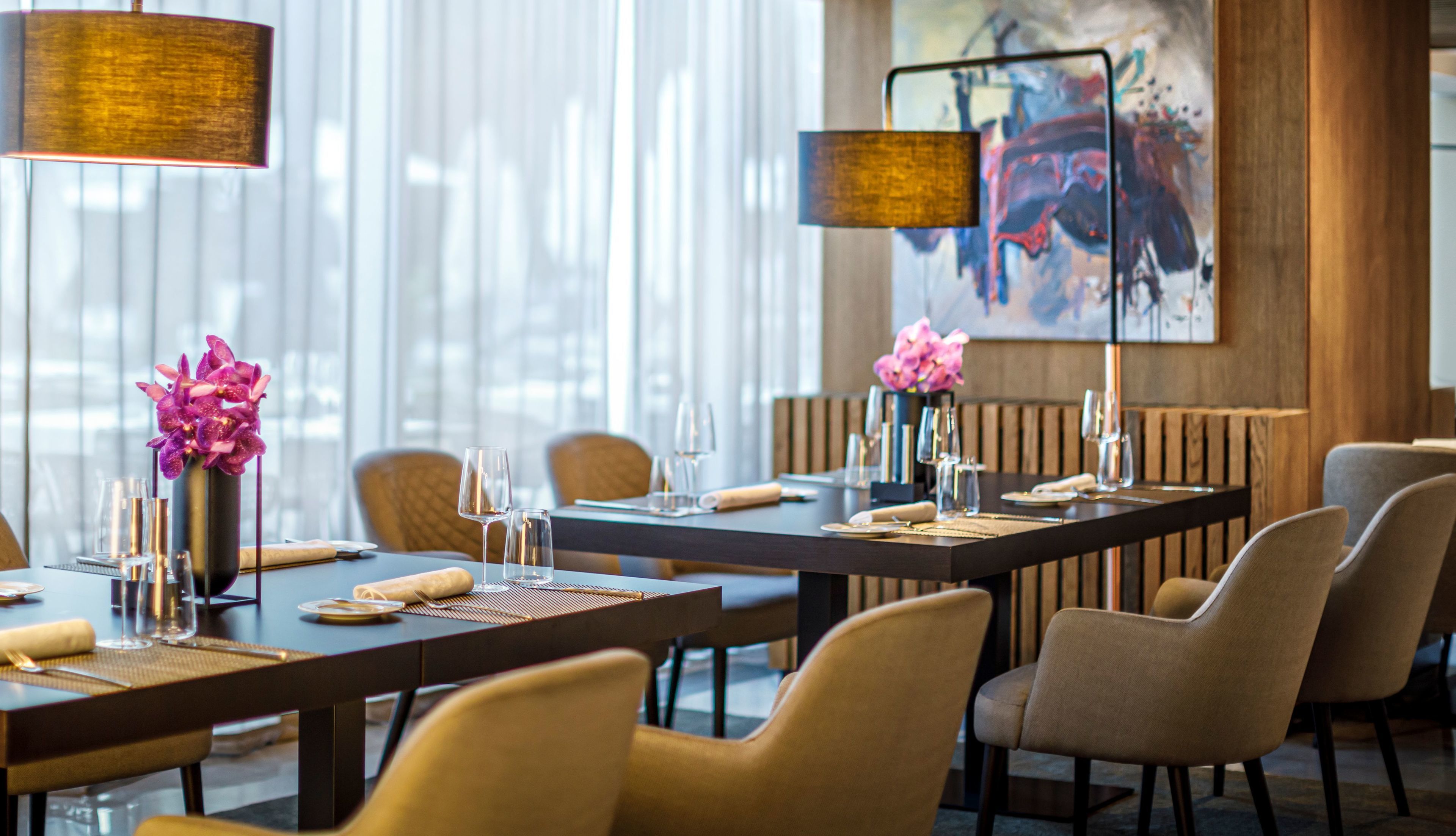Un espace repas moderne avec une longue table, des chaises et un vase rempli de fleurs roses.