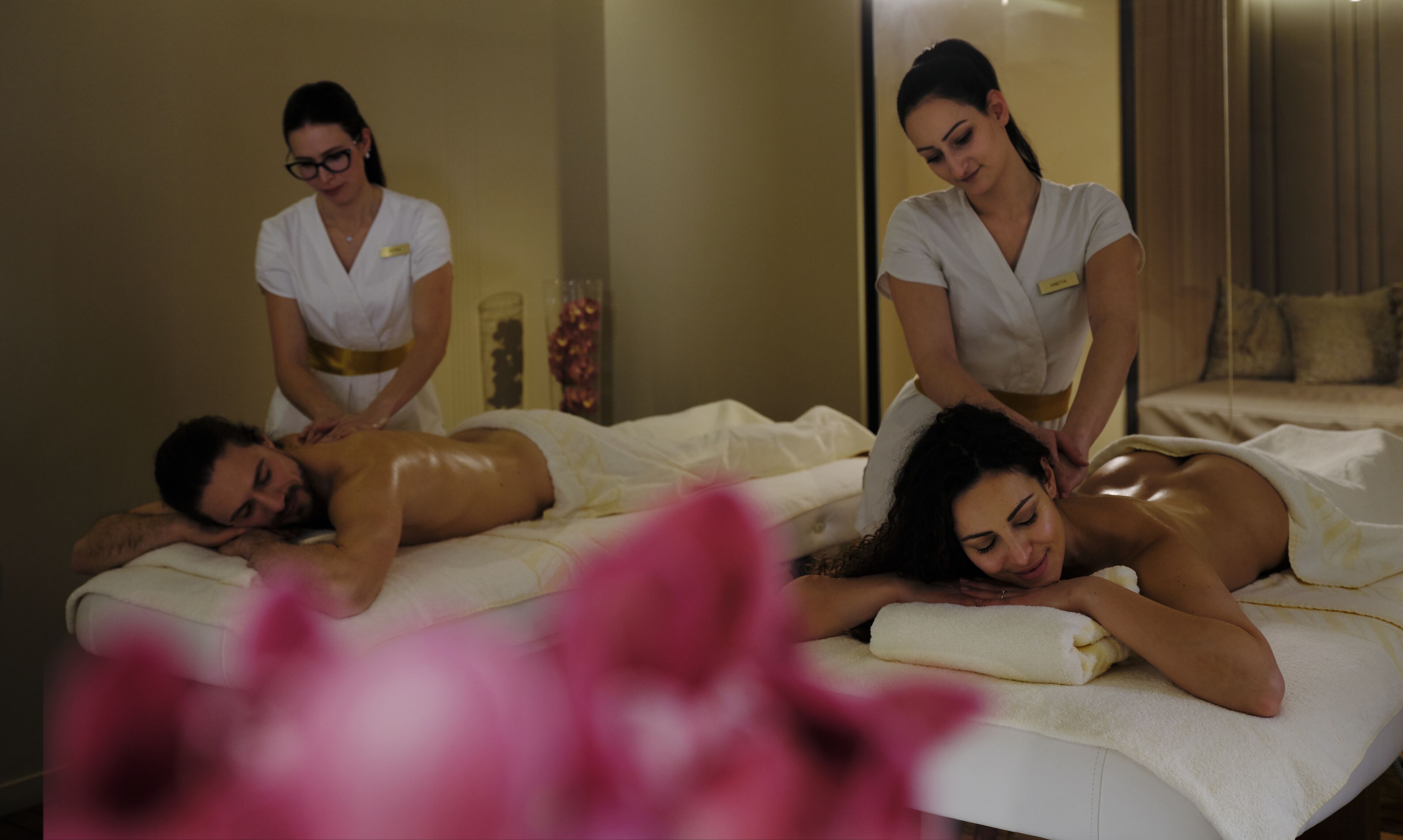 A massage therapy room with two clients receiving treatment from two therapists.