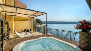 Un balcón con jacuzzi, sillones de descanso y vistas al lago.