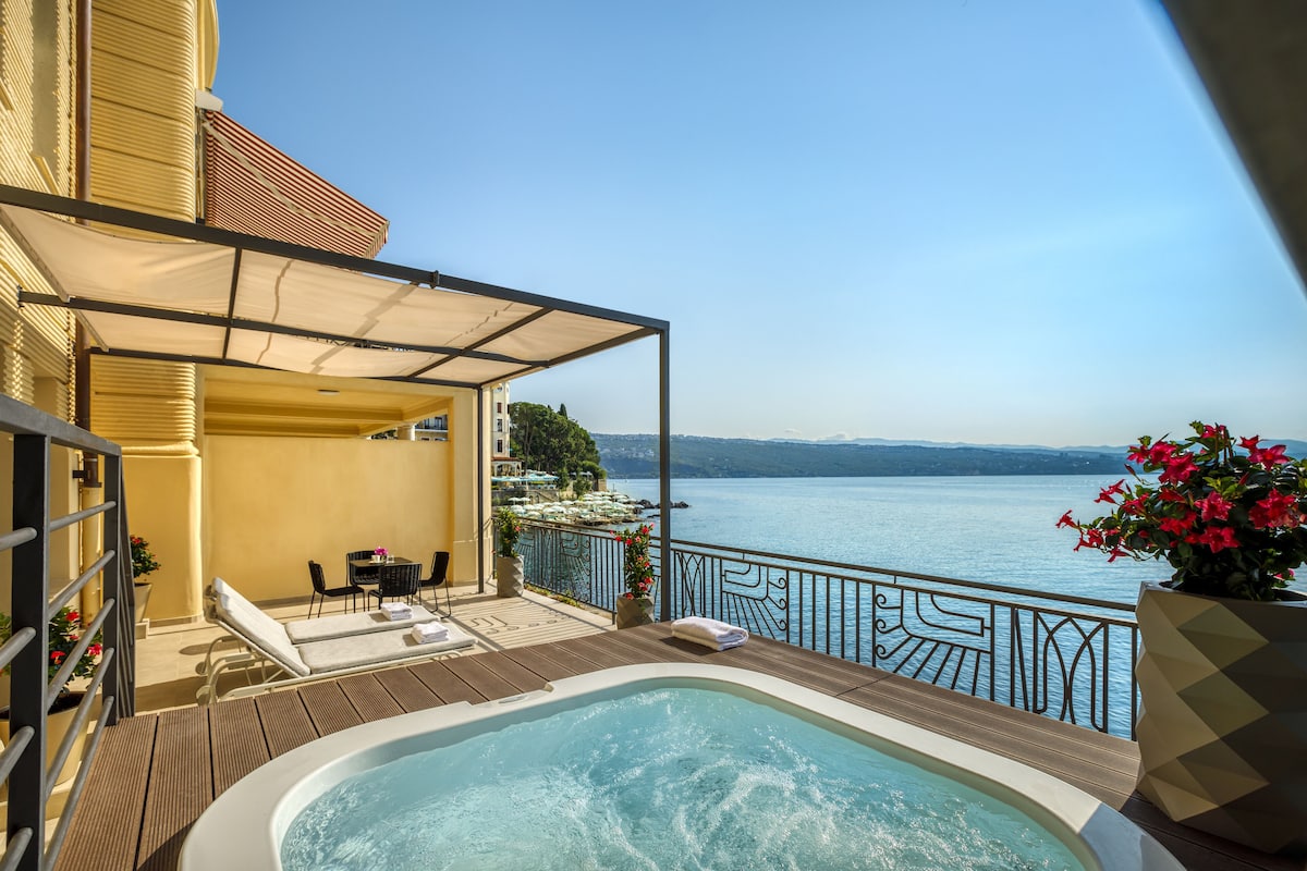 A balcony with a hot tub, lounge chairs, and a view of the lake.