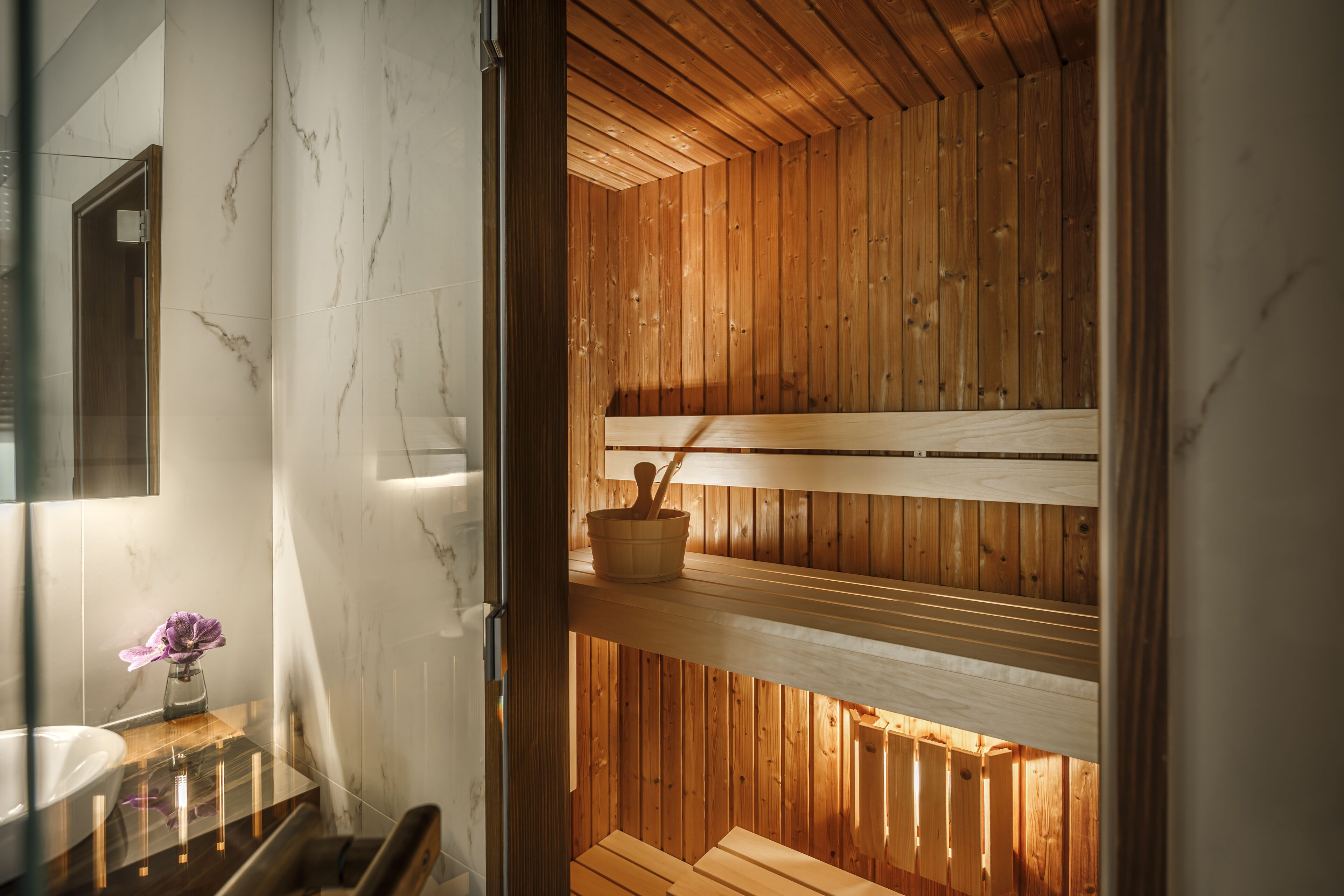Una sauna con bancos de madera y pared con azulejos de mármol.