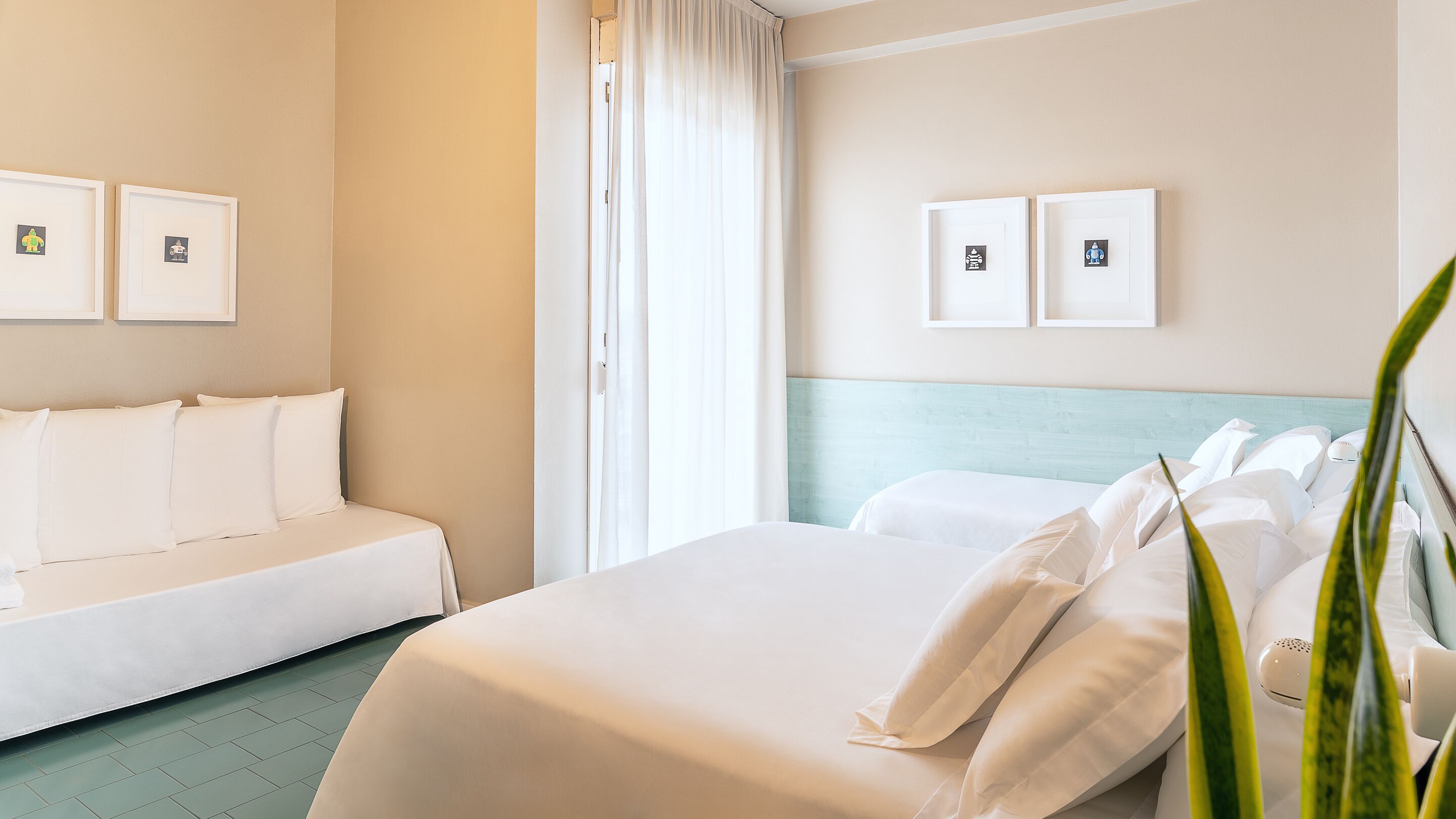 Ett hotellrum med en säng, en soffa och två inramade tavlor på väggen.