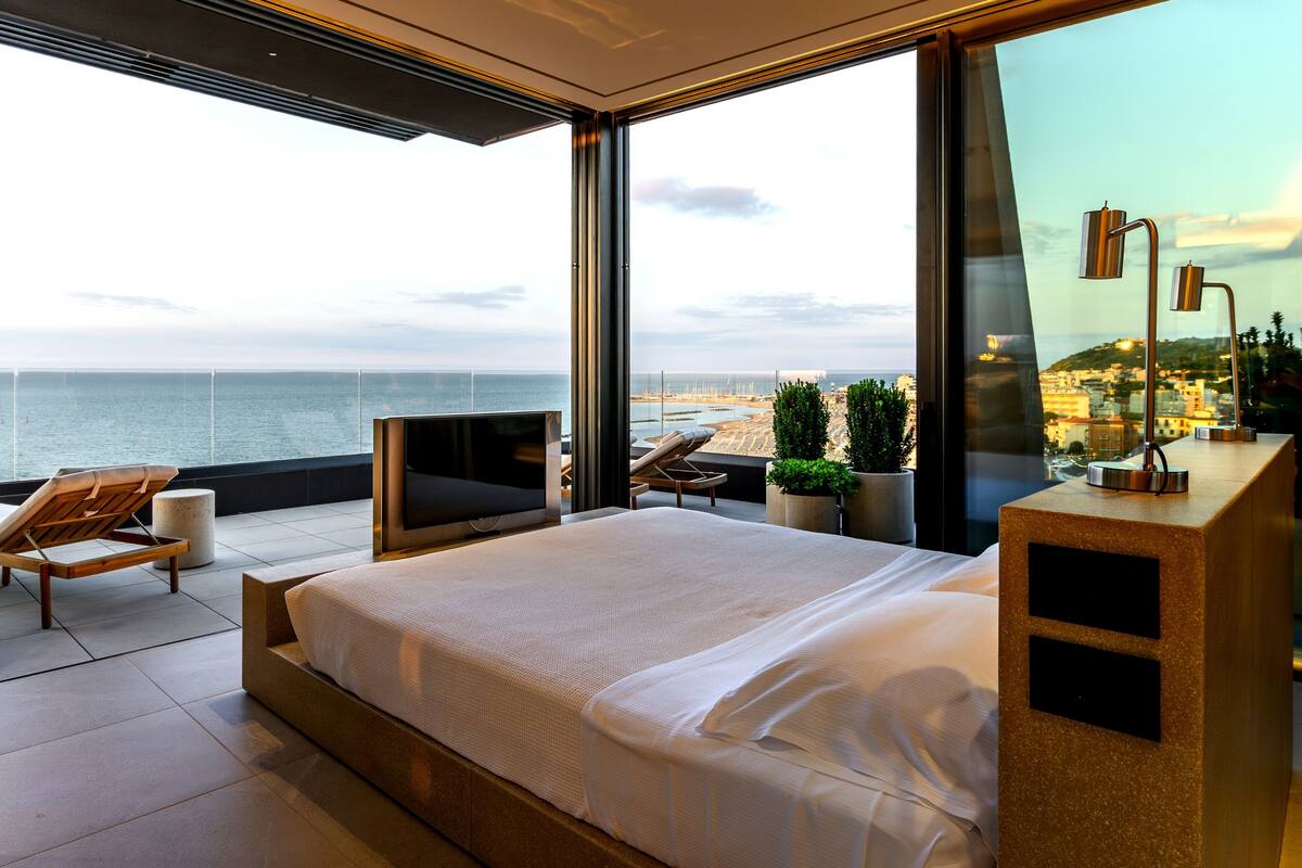 Una camera da letto moderna con un letto grande, una TV e vista sul mare.