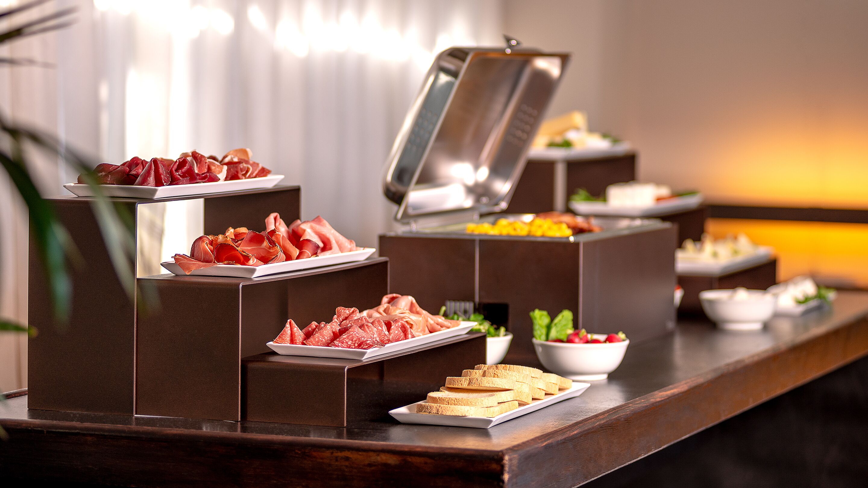 A buffet with various food items including meats, fruits, and vegetables.