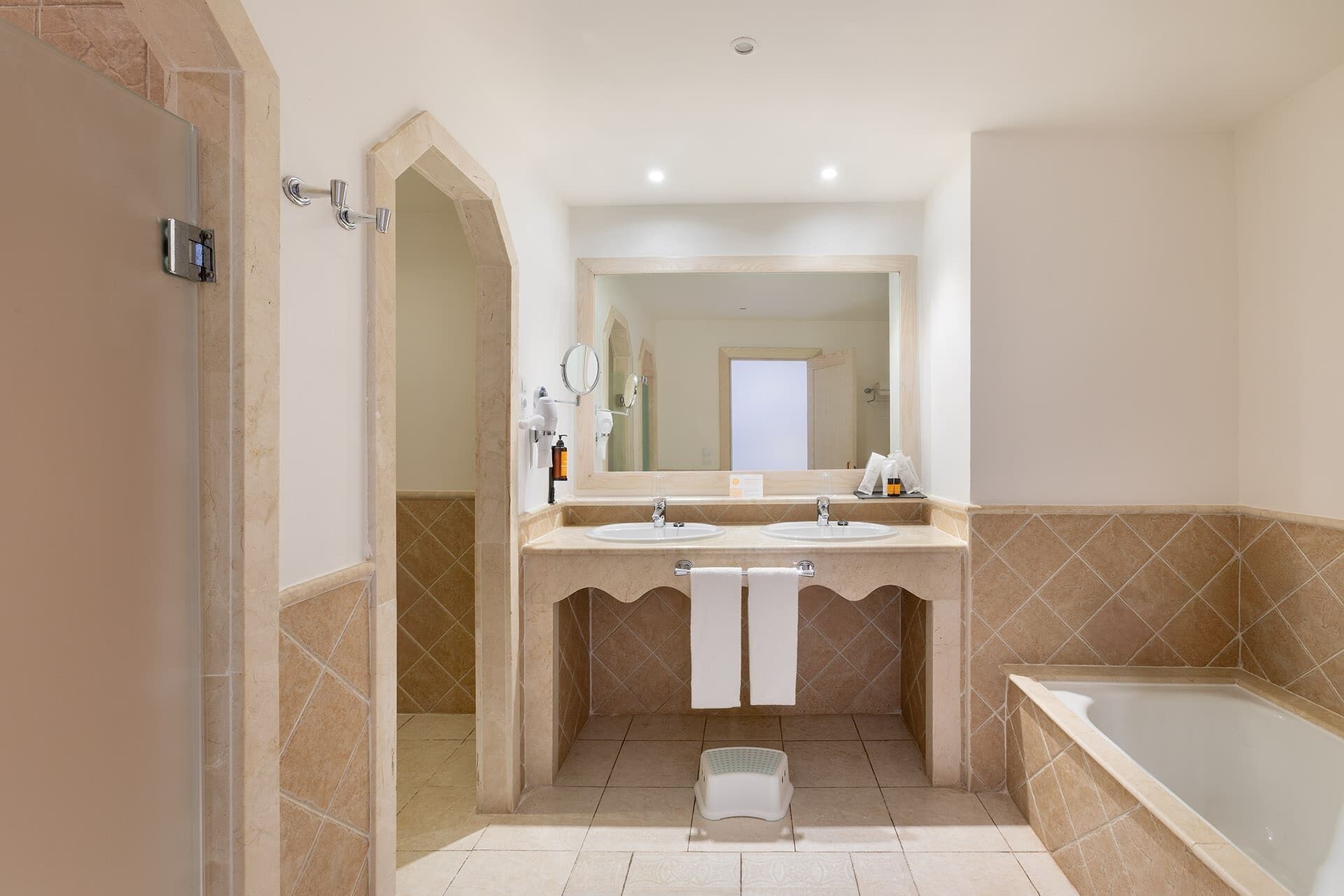 Un baño con dos lavamanos, un espejo grande, una bañera y una zona de ducha.