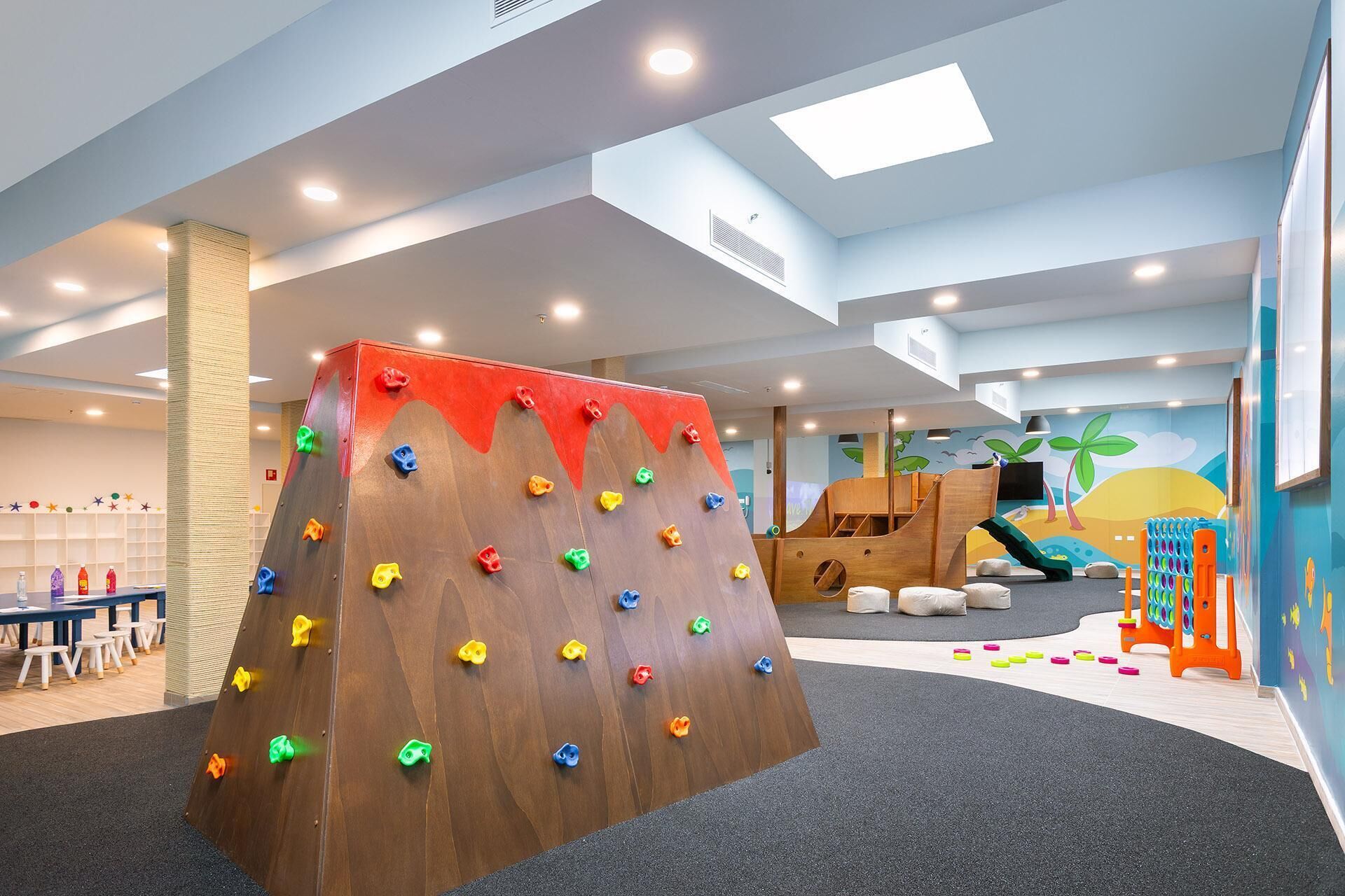 Un área infantil con pared de escalada, tobogán y casita.