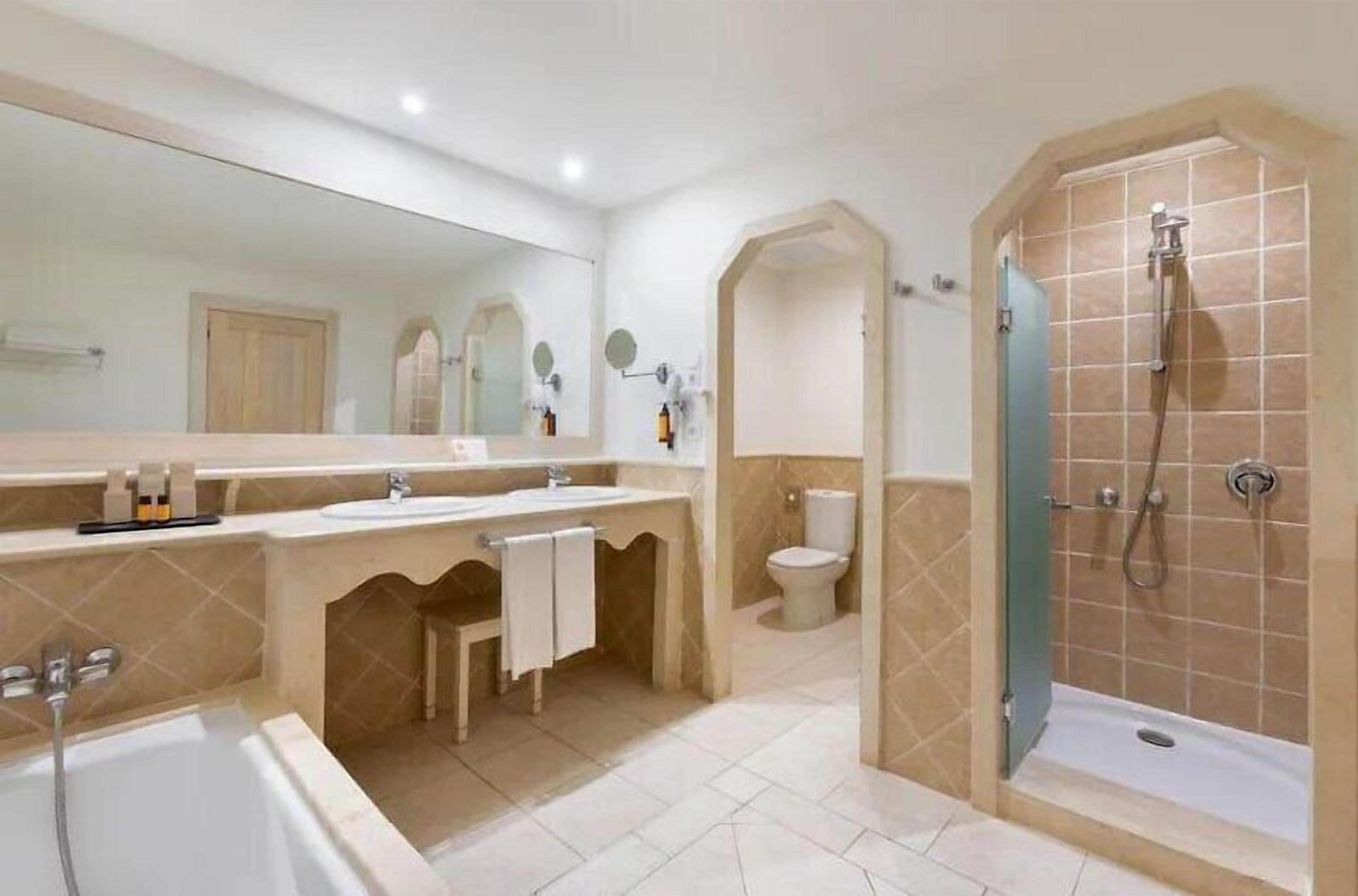 Een moderne badkamer met een bad, een douche en een toilet.