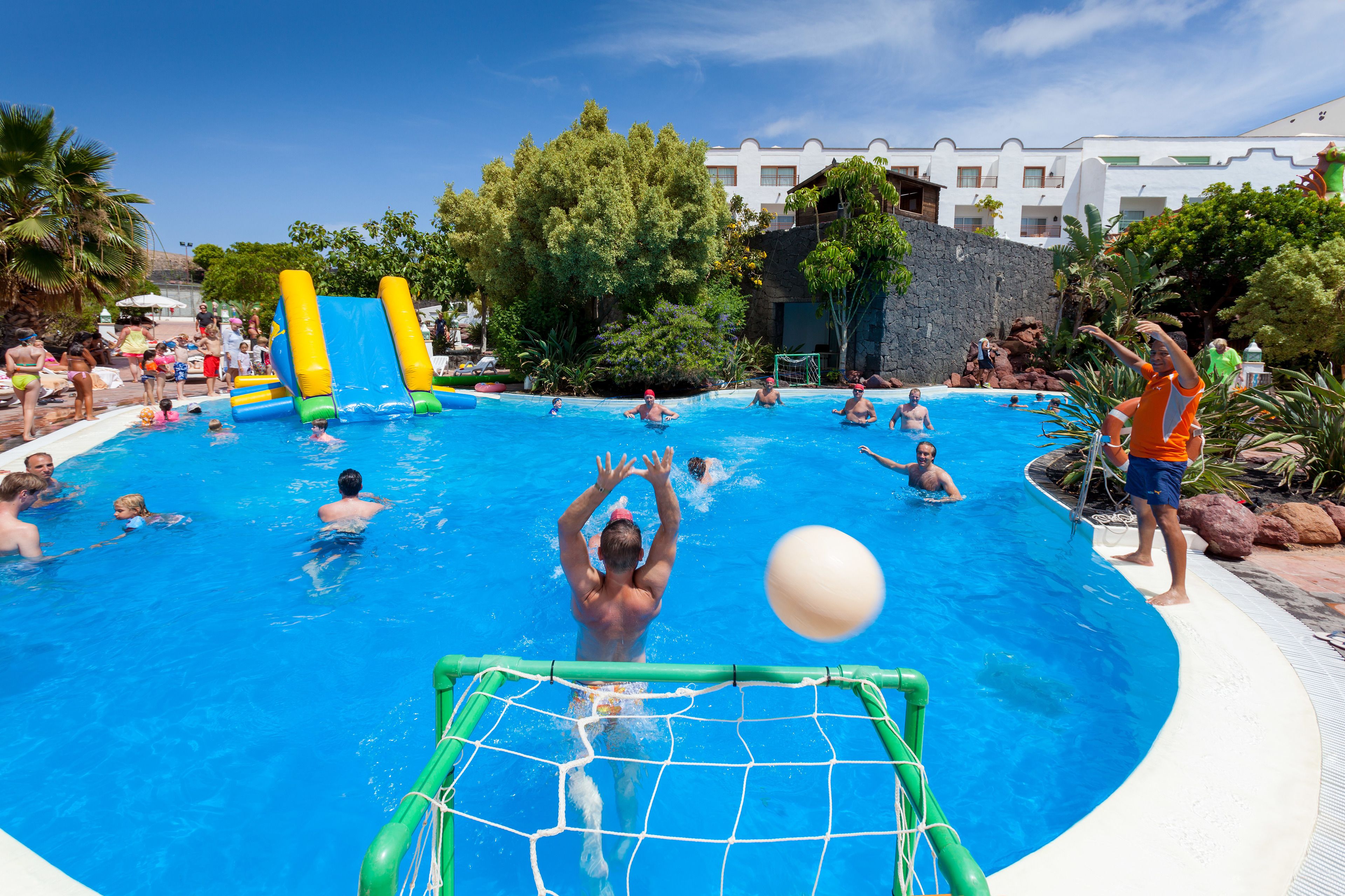 A swimming pool with inflatable slides and a netted goalpost.