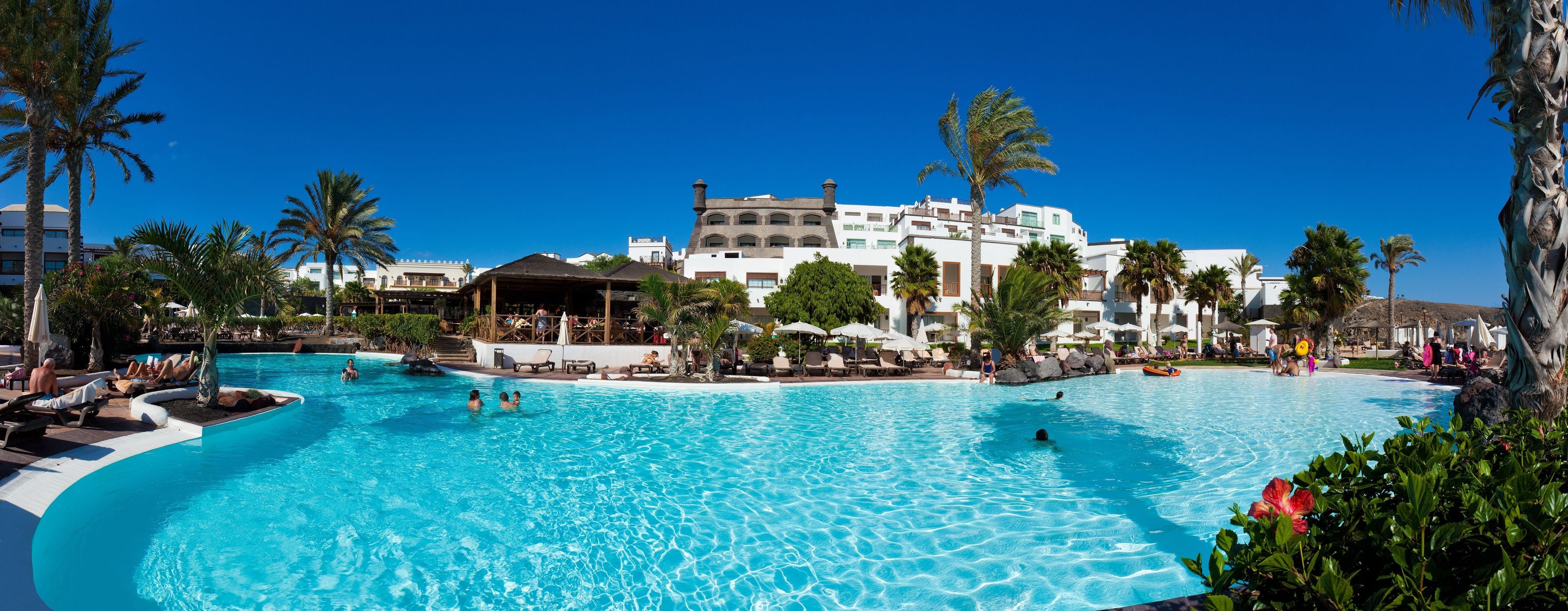 Una gran piscina al aire libre con varios niveles y palmeras.