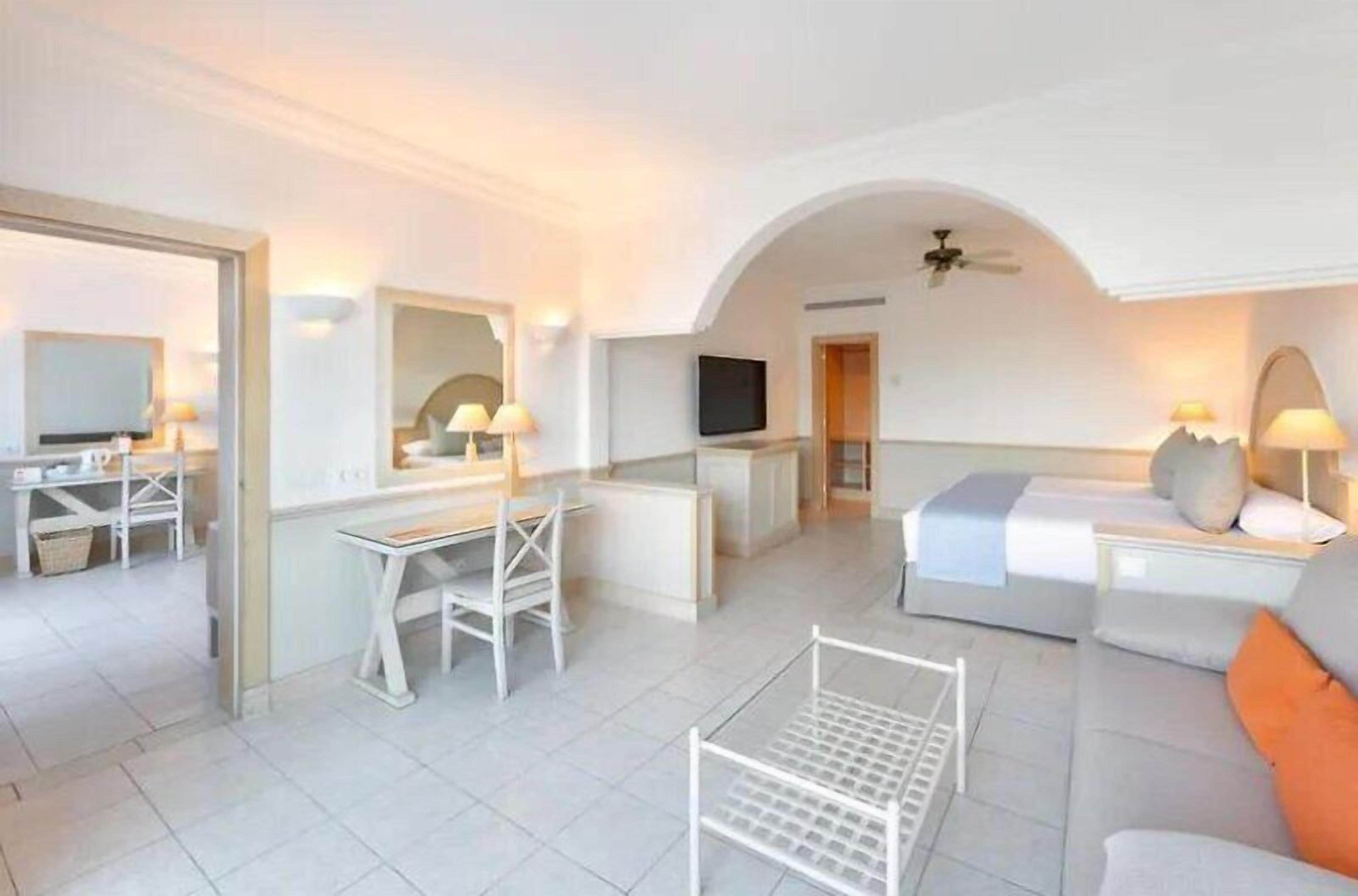 Una camera d'albergo moderna con una scrivania, un letto e una zona salotto.