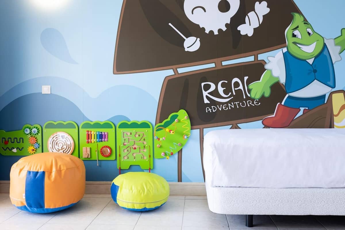 A child's playroom with a pirate-themed wall, a bed, and various educational toys.