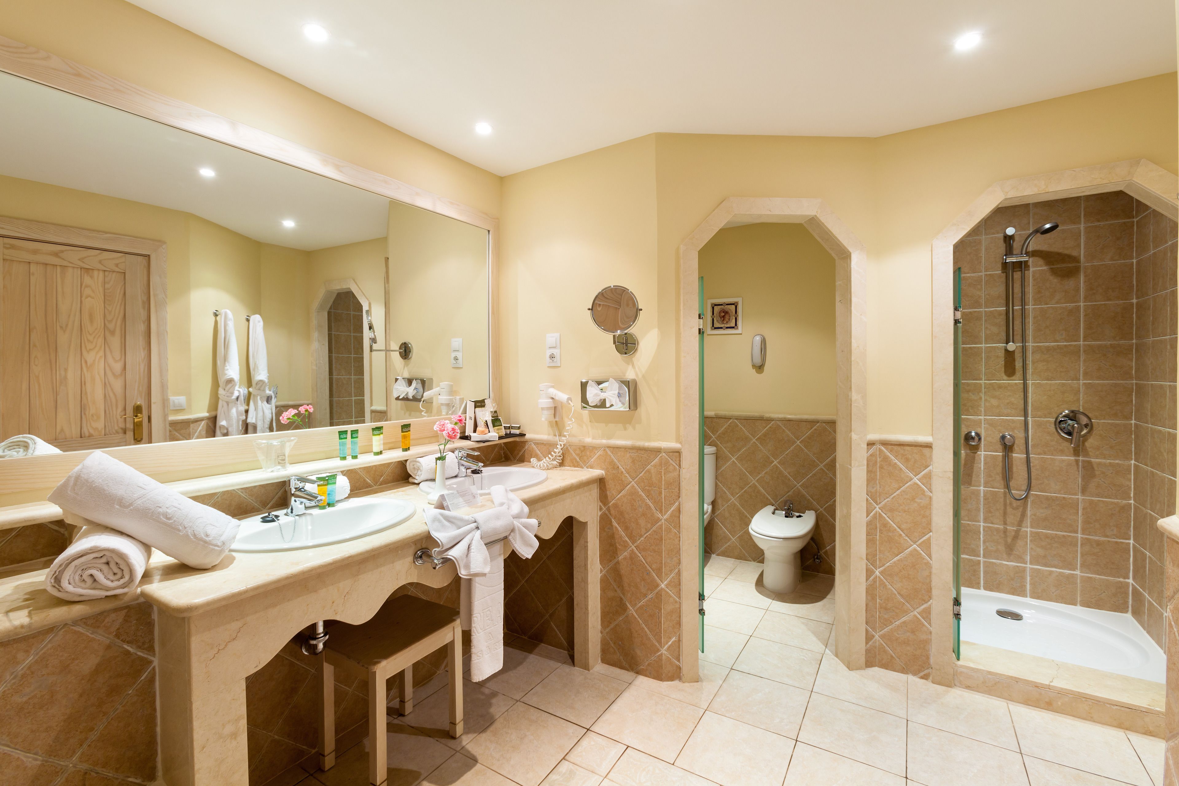 Une salle de bain avec deux lavabos, un grand miroir, une douche et des toilettes.