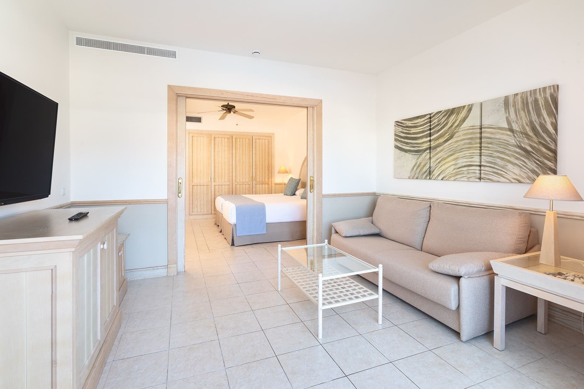 Ein modernes Hotelzimmer mit Bett, Sofa, Fernseher und einem Gemälde an der Wand.